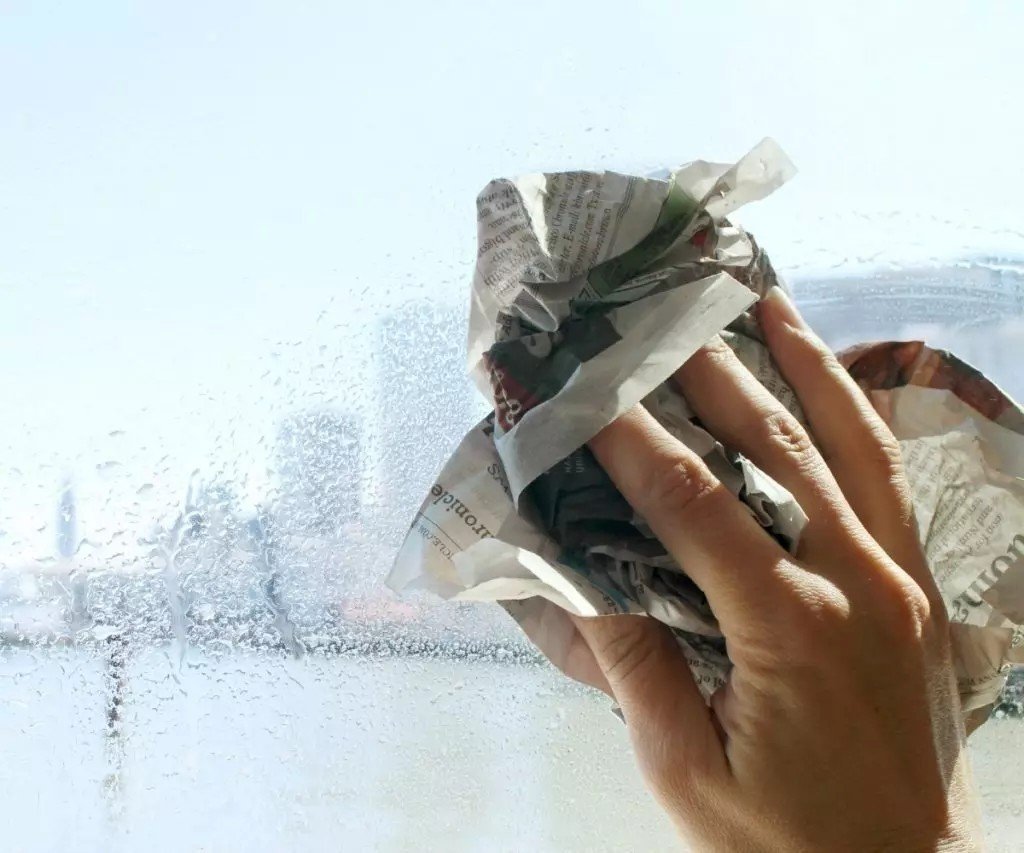 Мытье окна с помощью газеты
